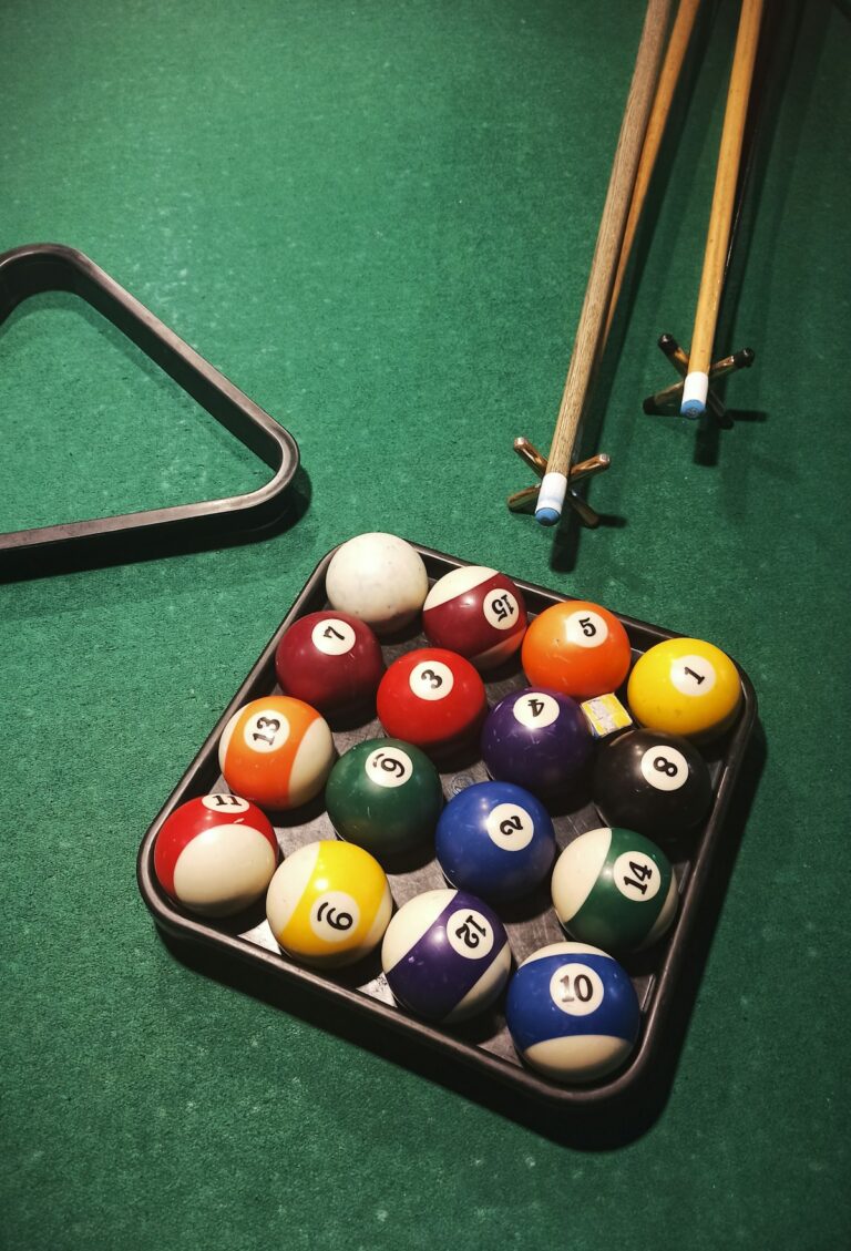 Pool table with rack of cues and billiard balls ready for play