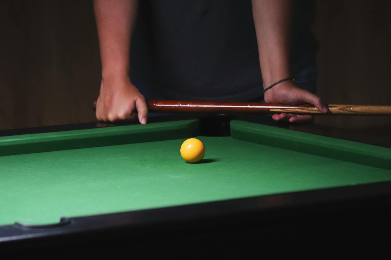 Pool player lining up a yellow ball on a green table, used for a WNT NXTGEN junior nineball article.