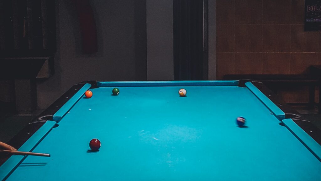 Pool table in a low-lit billiards room with balls and a cue, illustrating pool cue joint compatibility for a 2026 buyer guide